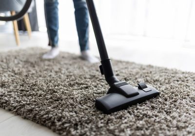 Close up of woman with legs vacuum cleaner cleaning carpet at home